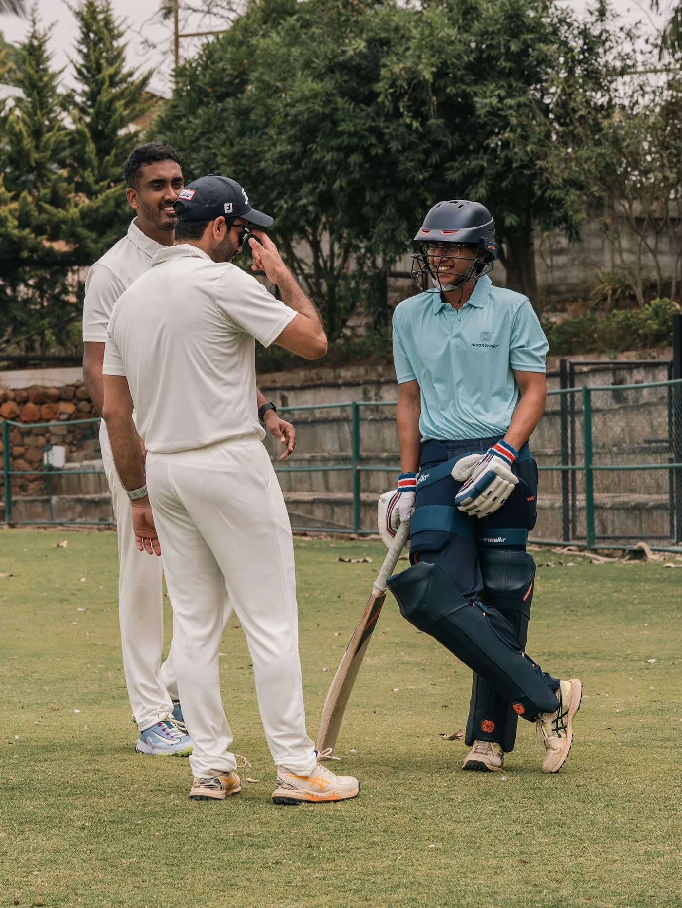 A coach talking a young cricketer through his batting at the nets